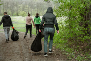 A group of volunteers with garbage bags are cleaning the forest. Agrupaciones de propietarios de bosques